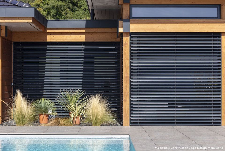 Brise-soleil noir sur façade bois avec piscine devant