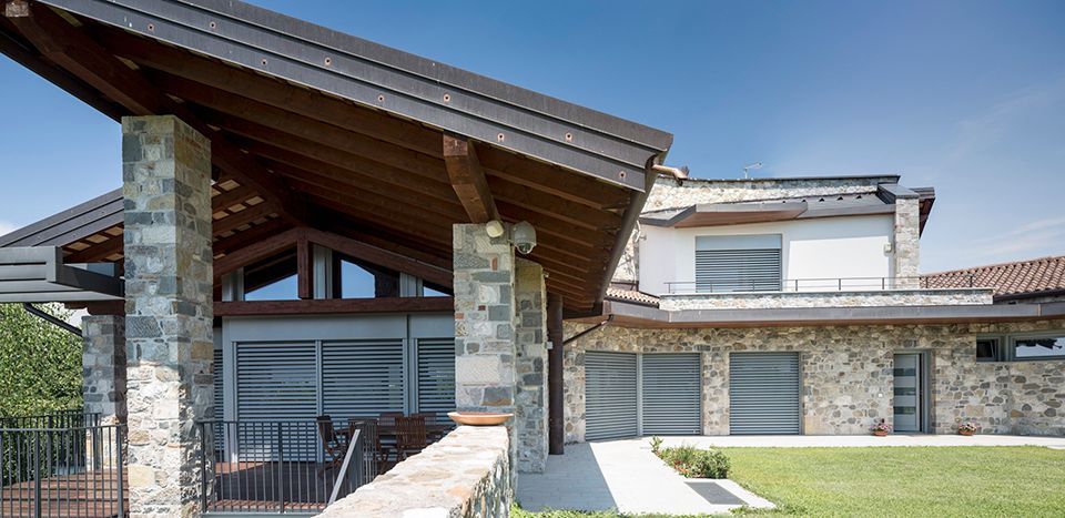 Grande maison avec nombreuses ouvertures et brise-soleil gris pour protéger celle-ci