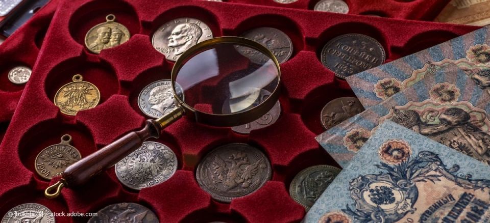 Goldschmuck, darunter Ohrringe, Ringe und eine Halskette, auf einem cremefarbenen Tuch ausgestellt.