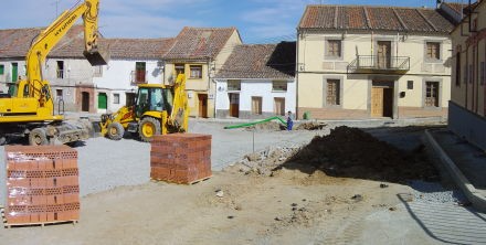 Un sitio de construcción con ladrillos y una excavadora amarilla