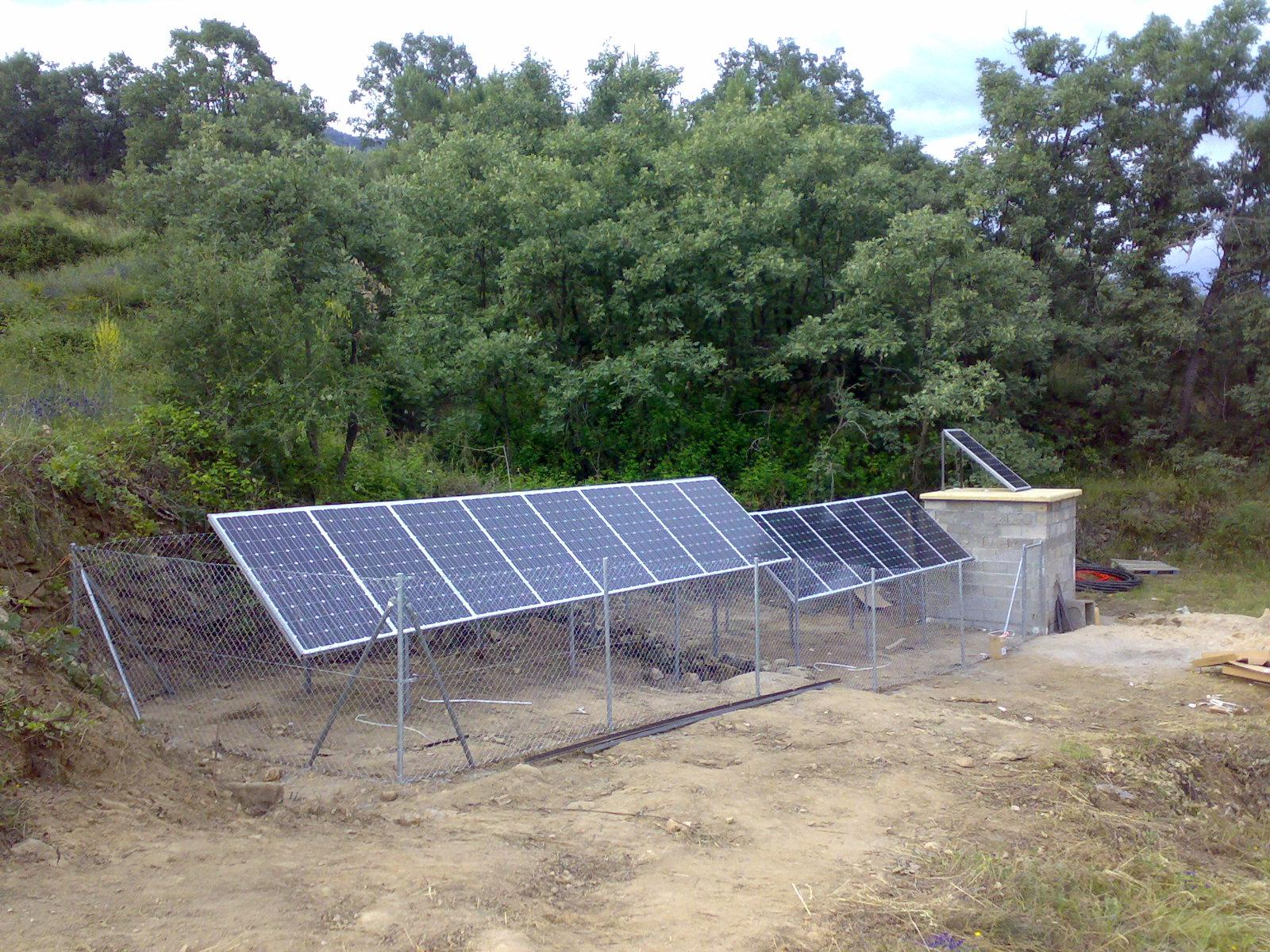 Una fila de paneles solares están ubicados sobre un campo de tierra.