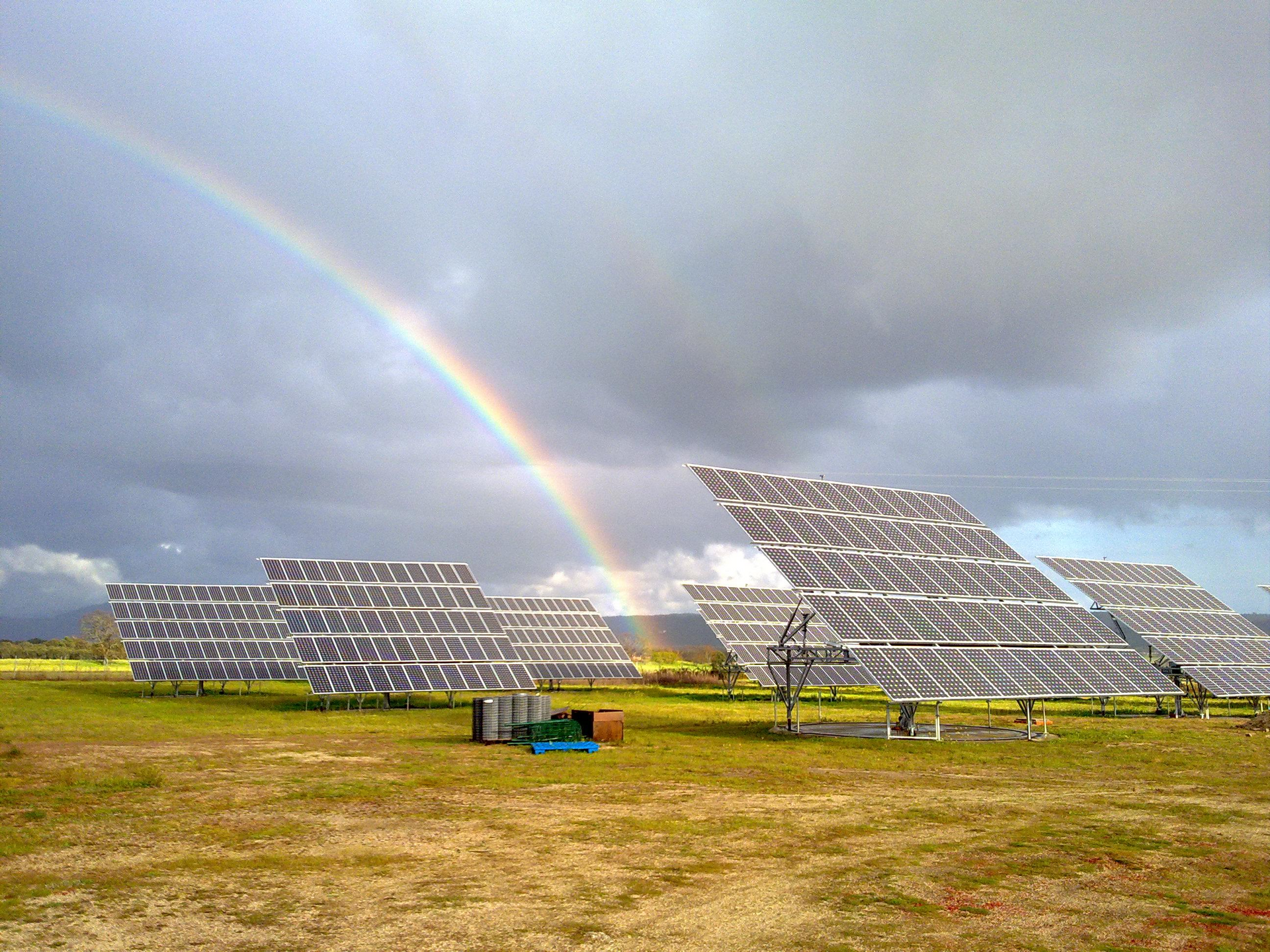 Se ve un arcoíris sobre un campo de paneles solares.