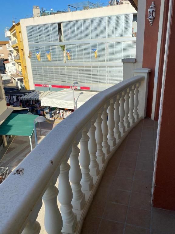 Balcón con vistas a una calle con edificios y toldos, balaustrada blanca en primer plano.