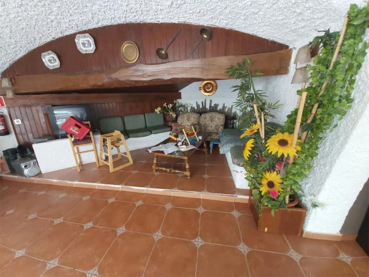 Interior con baldosas de terracota, techo con vigas de madera, zona de estar y girasoles.