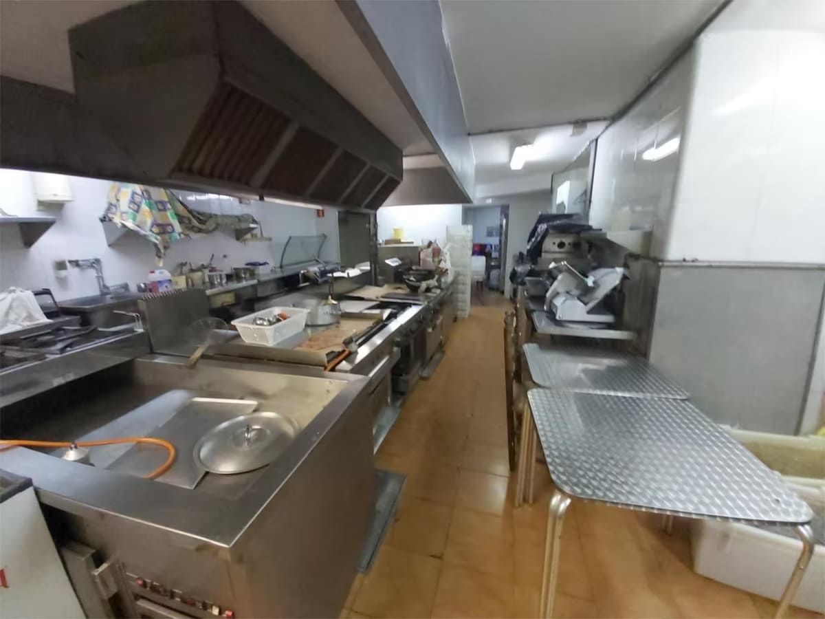 Cocina comercial con electrodomésticos de acero inoxidable y campanas de ventilación.