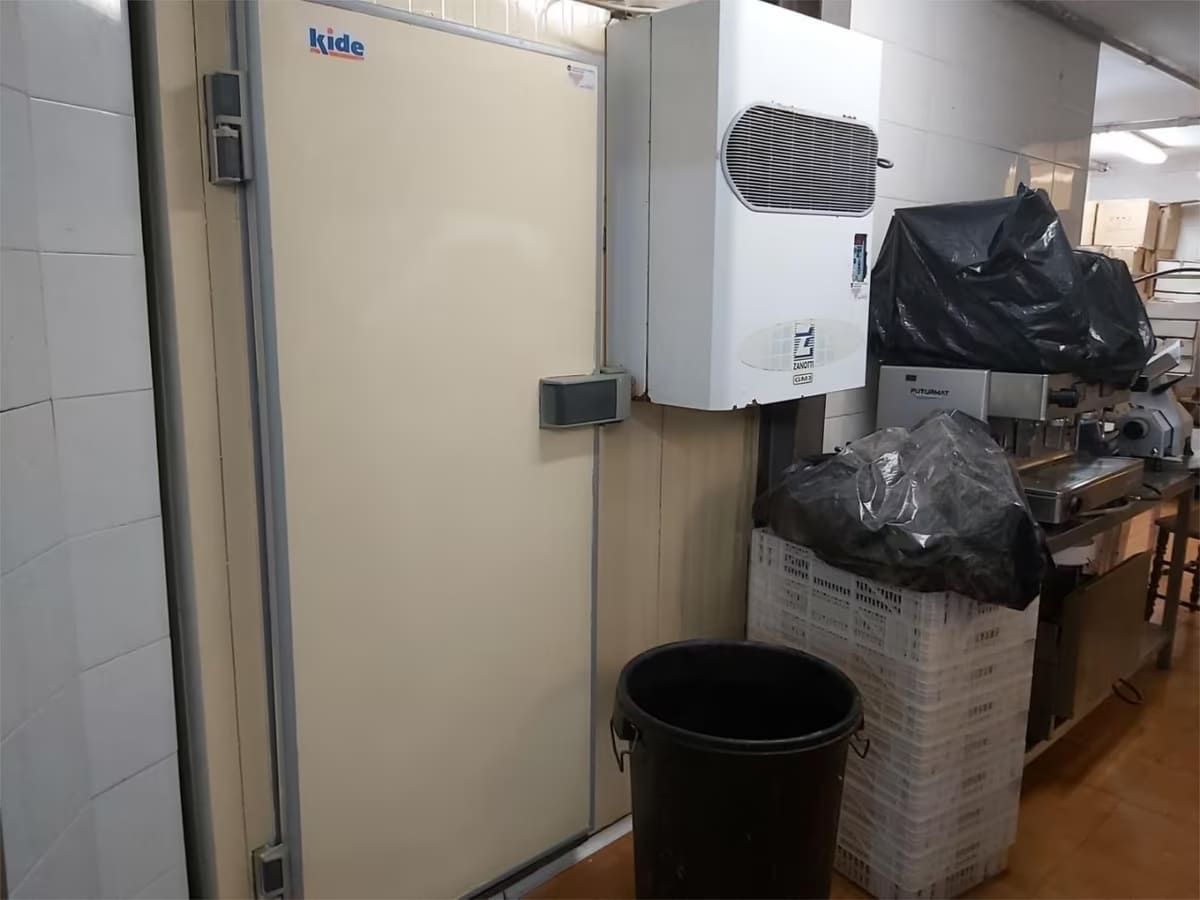 Una puerta de refrigerador, montada con una unidad enfriadora, al lado de basura y suministros.