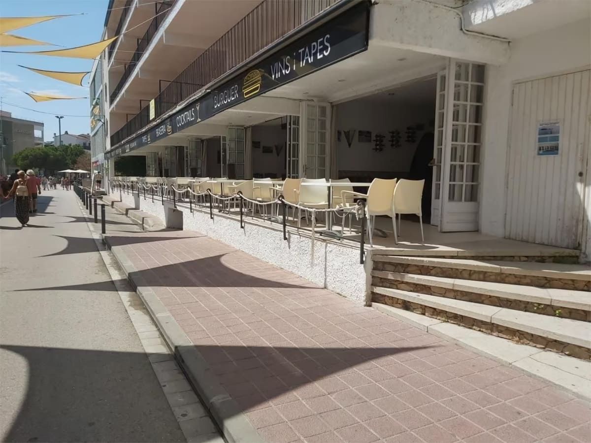 Exterior de un restaurante con mesas al aire libre en la acera. Sombrillas amarillas en el techo.
