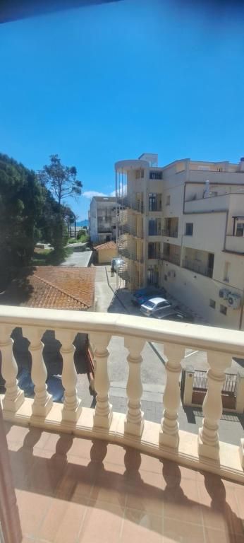 Vista desde un balcón de edificios de apartamentos de color beige, coches aparcados y cielo azul en un día soleado.