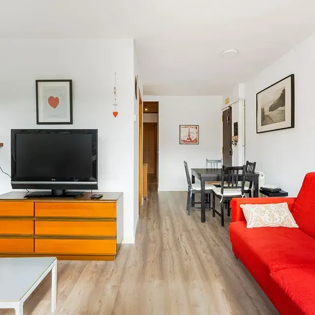 Una sala de estar con un sofá rojo y un televisor de pantalla plana.