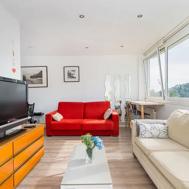 Una sala de estar con un sofá rojo y un televisor de pantalla plana.