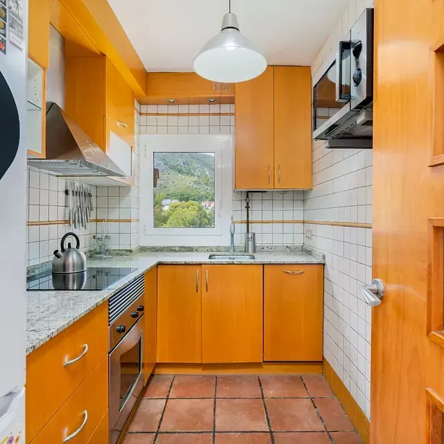 Una cocina con gabinetes naranjas y una ventana.