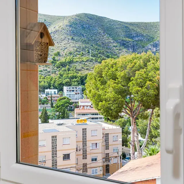 Una vista de una ciudad desde una ventana con montañas al fondo.