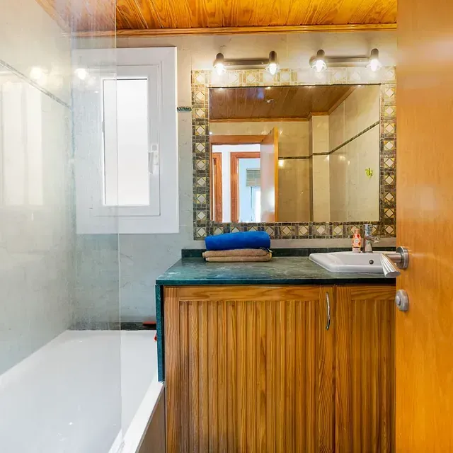 Un baño con lavabo, bañera, espejo y ventana.