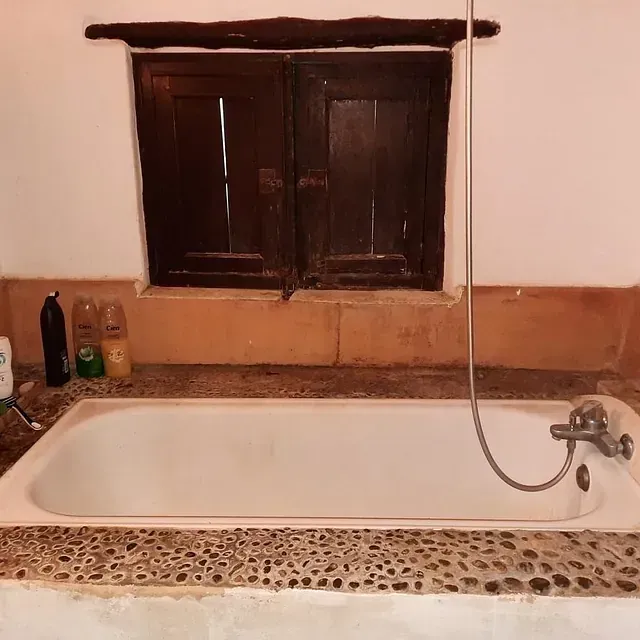 Una bañera en un baño al lado de una ventana.