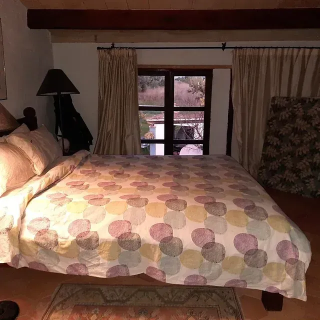 Un dormitorio con un edredón de lunares y una lámpara.