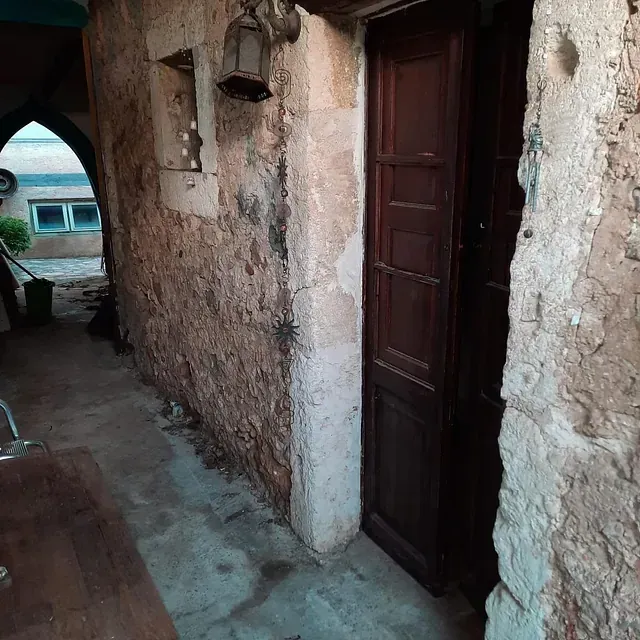Un antiguo edificio de piedra con una puerta de madera y una linterna en la pared.
