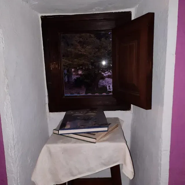 Una mesa con libros encima frente a una ventana.