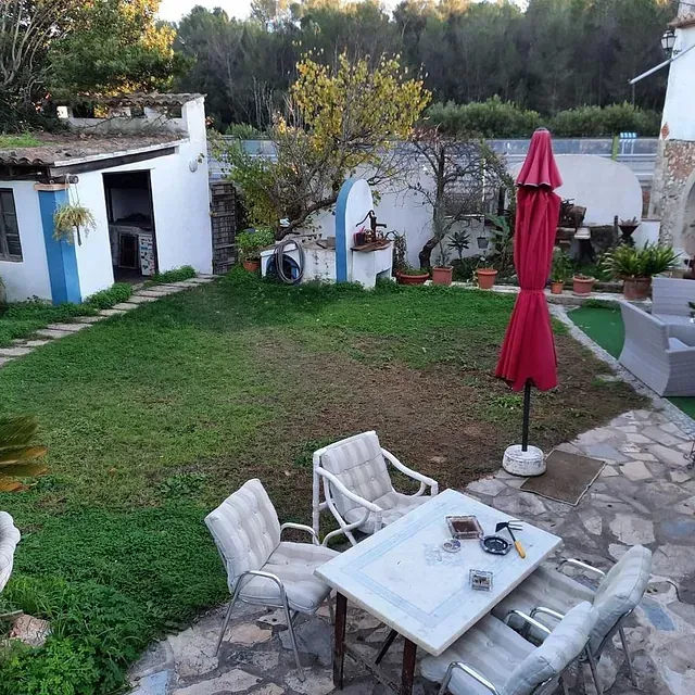 Un patio con una mesa y sillas y una sombrilla roja.