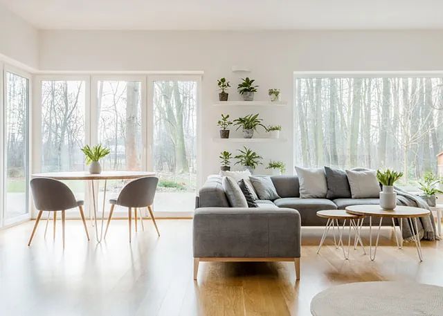 Una sala de estar con sofá, mesa, sillas y muchas ventanas.