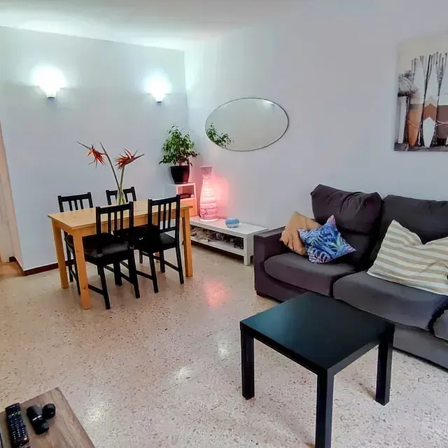 Una sala de estar con un sofá, una mesa y sillas.