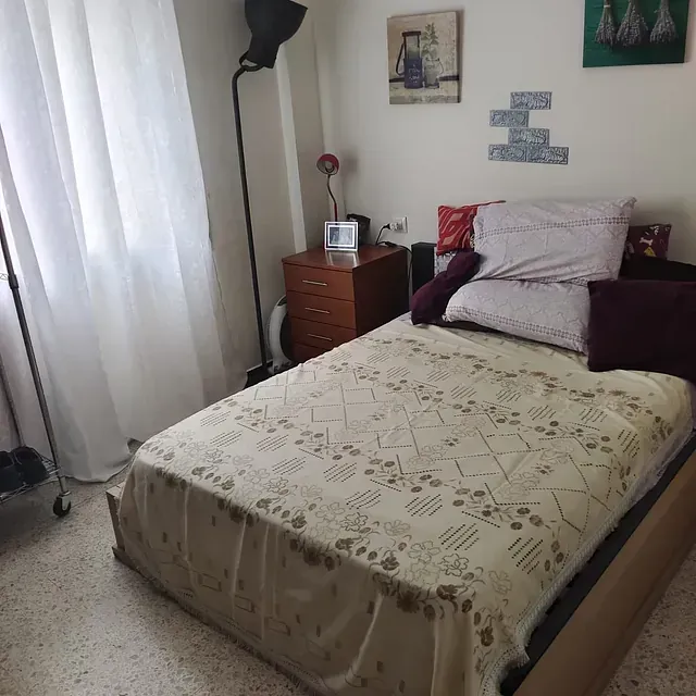 Un dormitorio con una cama, una mesita de noche y una lámpara.