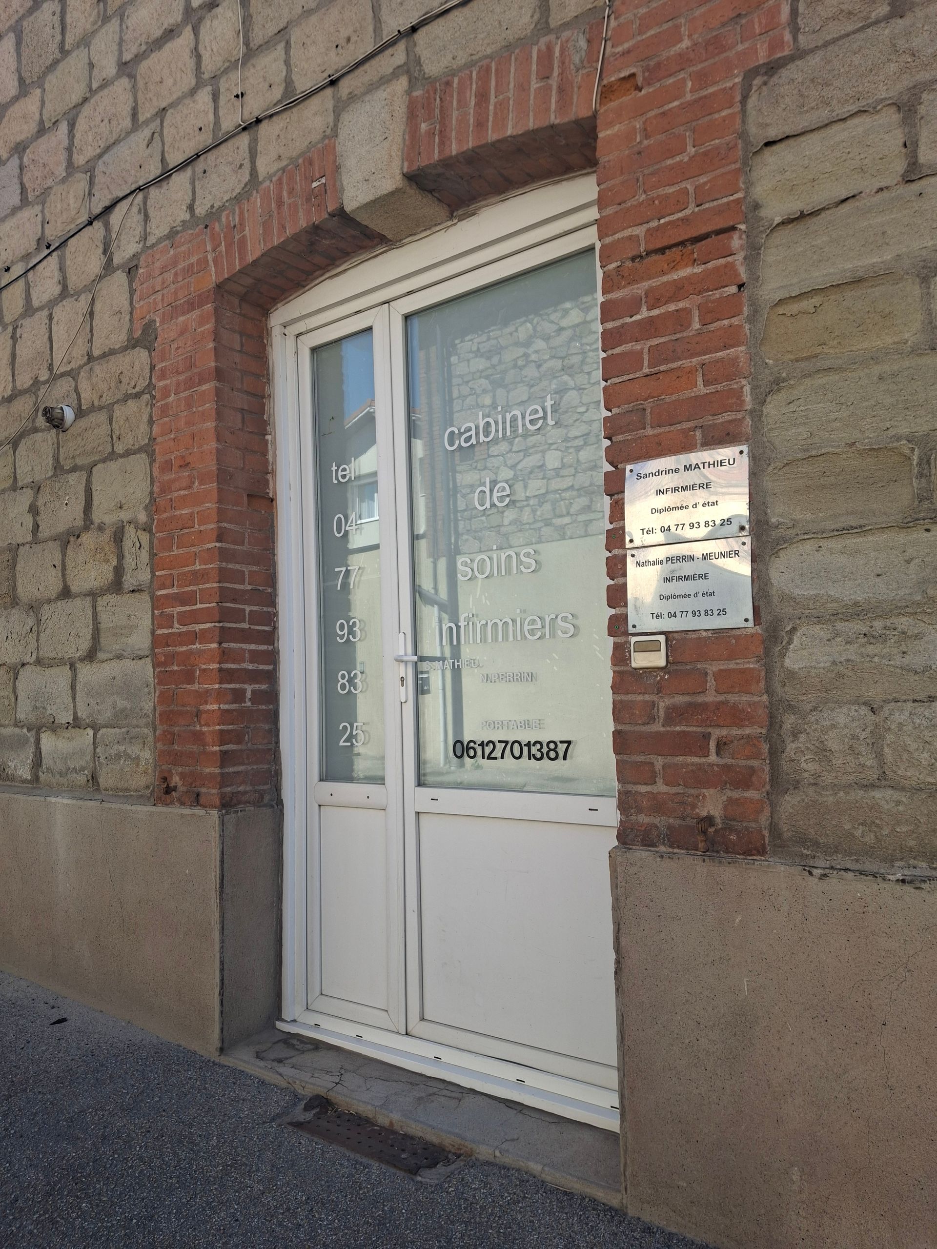 Façade en briques avec porte vitrée blanche et affiches sur la vitrine et le mur