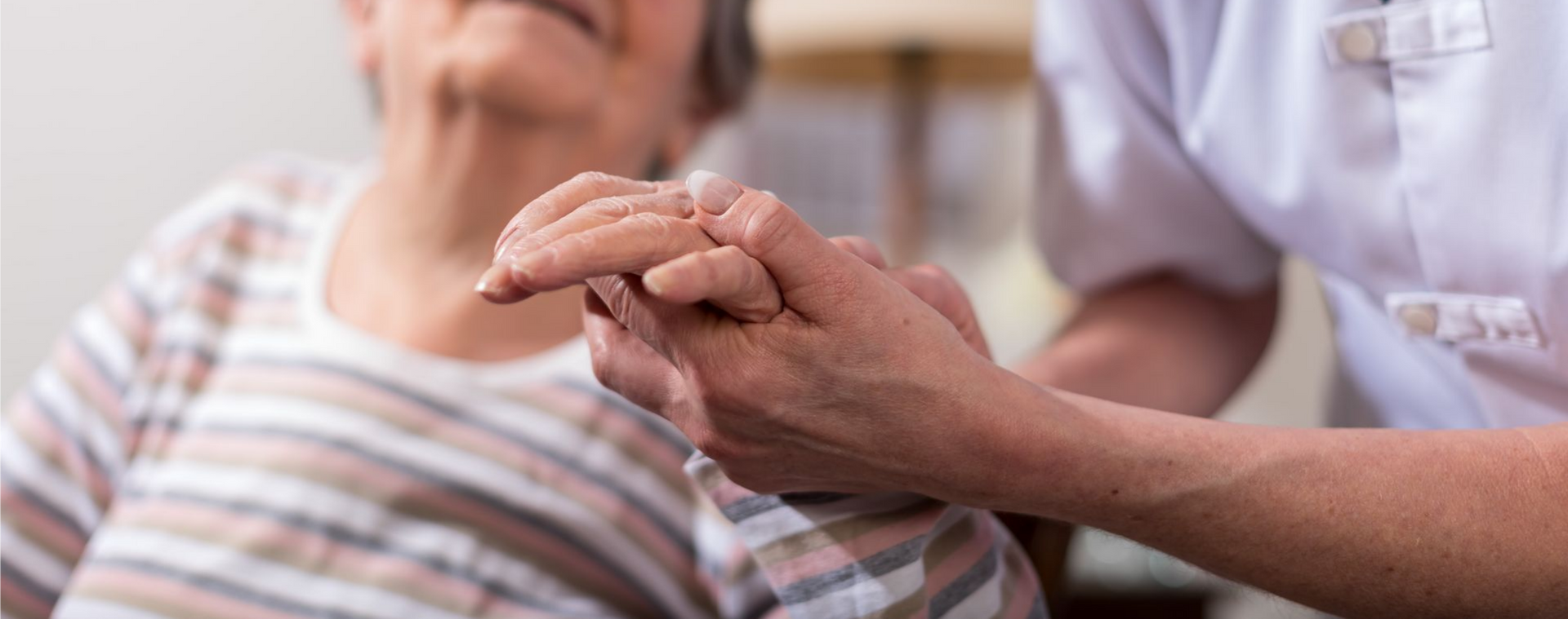 Un agent de santé tient délicatement la main d'un patient dans un environnement clinique