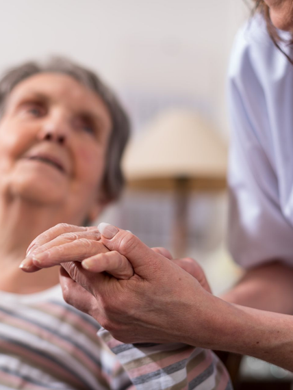 Des mains tenant délicatement la main d'une personne âgée dans un établissement de soins