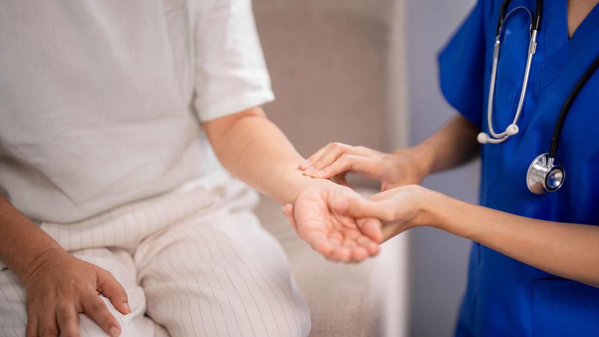 Un professionnel de santé vérifie le pouls d'un patient assis sur un divan