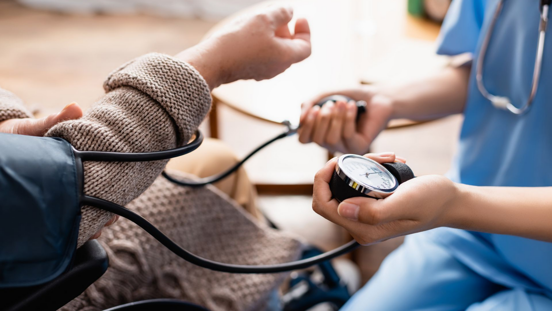 Un professionnel de santé prend la tension artérielle d'un patient allongé sur un divan.