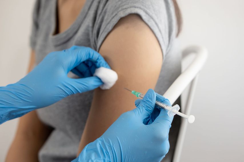 Un professionnel de santé ganté administre une injection de vaccin dans le haut du bras d'un patient