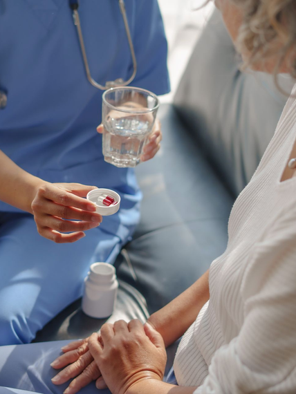 Une infirmière donne un comprimé et de l'eau à un patient dans une chambre d'hôpital.