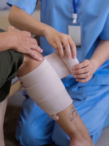 Une infirmière pose un bandage autour du genou d'un patient dans une clinique