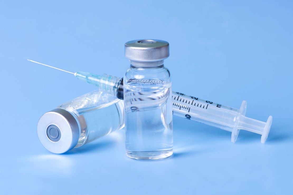 Flacon de vaccin avec seringue et aiguille protégée sur fond bleu