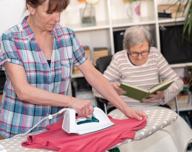 Eine Pflegekraft bügelt Kleidung