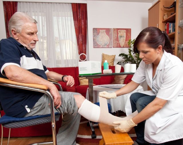 Eine Pflegekraft wechselt die Bandage eines Herren