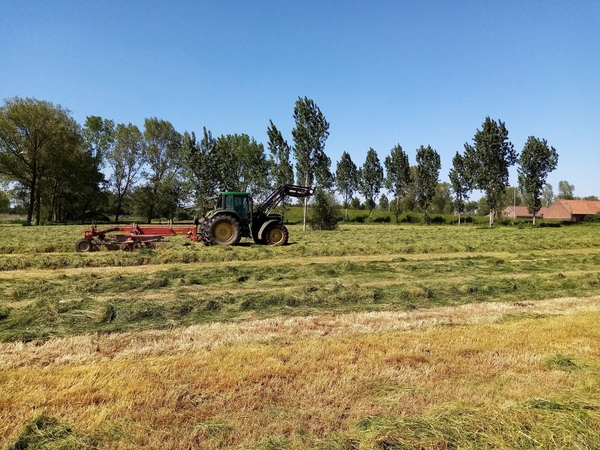 gras harken met een groene tractor van John Deere