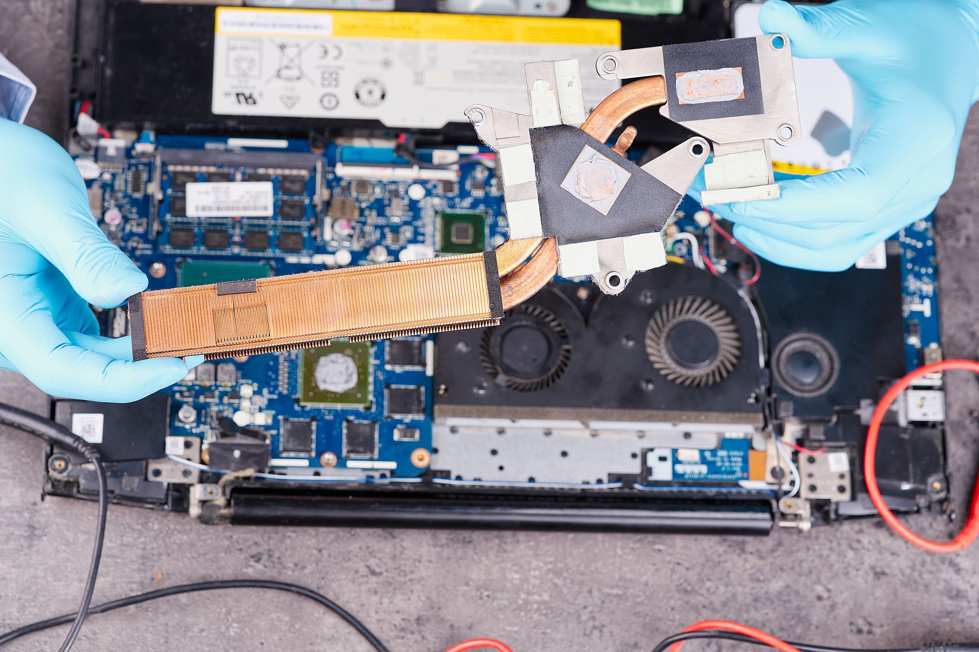 Una persona que lleva guantes azules está trabajando en una computadora portátil.