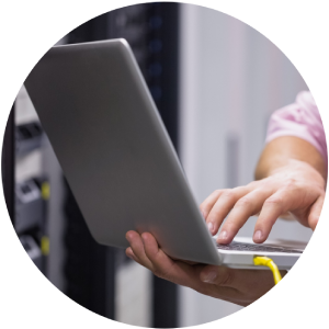 Una persona está escribiendo en una computadora portátil en una sala de servidores.