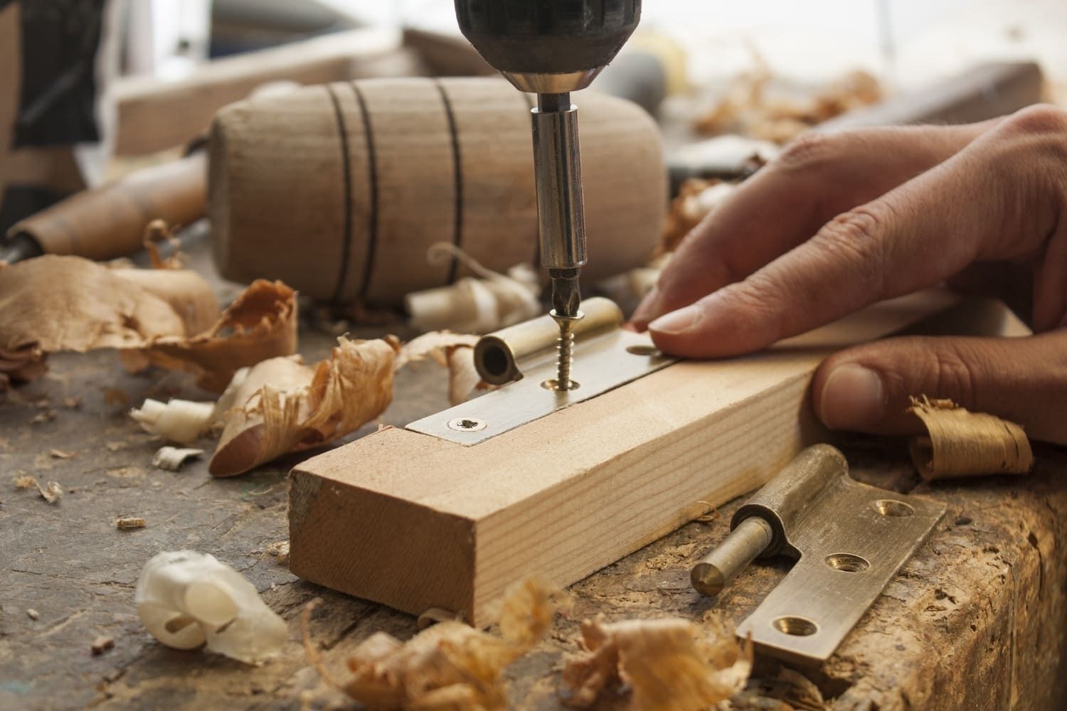 Una persona está usando un taladro para hacer un agujero en un trozo de madera.