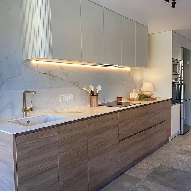 Una cocina con gabinetes de madera, un fregadero, una estufa y un refrigerador.