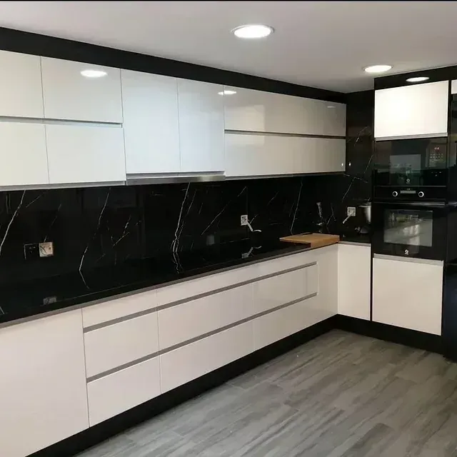 Una cocina con encimeras negras y gabinetes blancos.