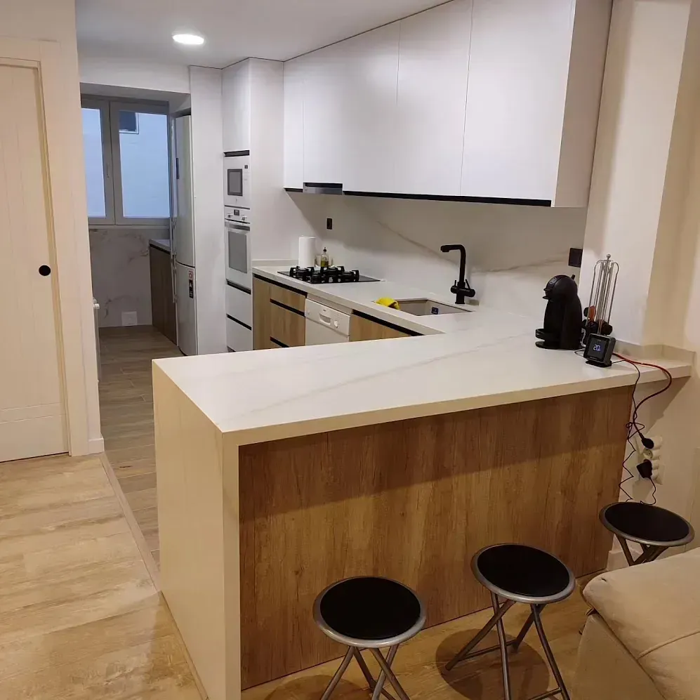Una cocina con gabinetes blancos y encimeras de madera.