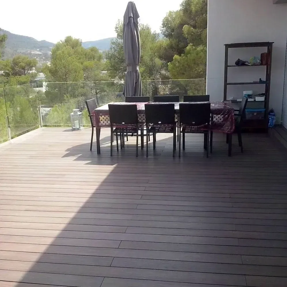 Una terraza de madera con una mesa y sillas.