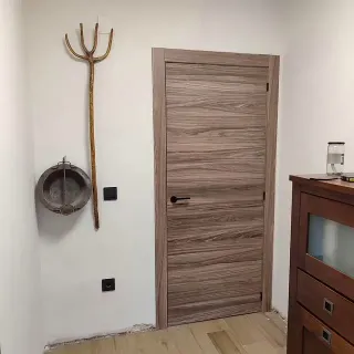 Una habitación con una puerta de madera y un tridente en la pared.