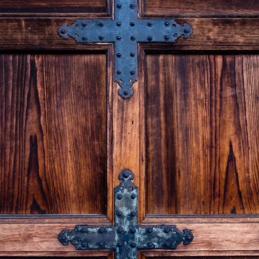 Una puerta de madera con una cruz de metal sobre ella.