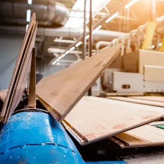 Una máquina está cortando madera contrachapada en una fábrica.