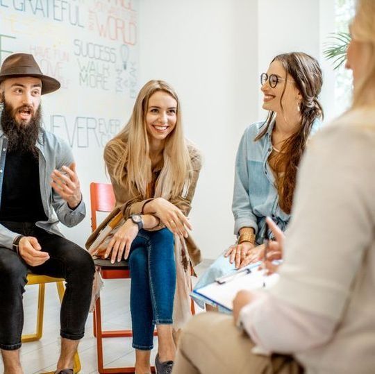 Un grupo de personas están sentadas en círculo hablando entre sí.