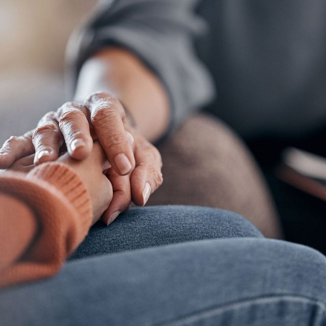 Manos juntas; una mano mayor sosteniendo una mano más joven, ofreciendo consuelo.