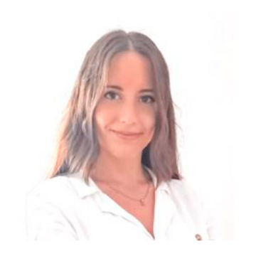 Una mujer con una bata blanca y un collar sonríe a la cámara.